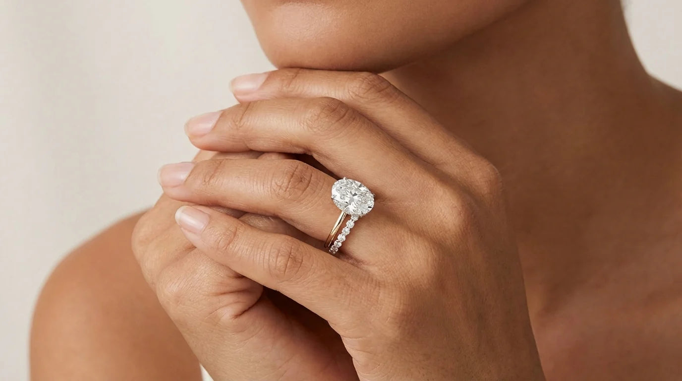Close-up of a hand wearing a diamond ring on a neutral background