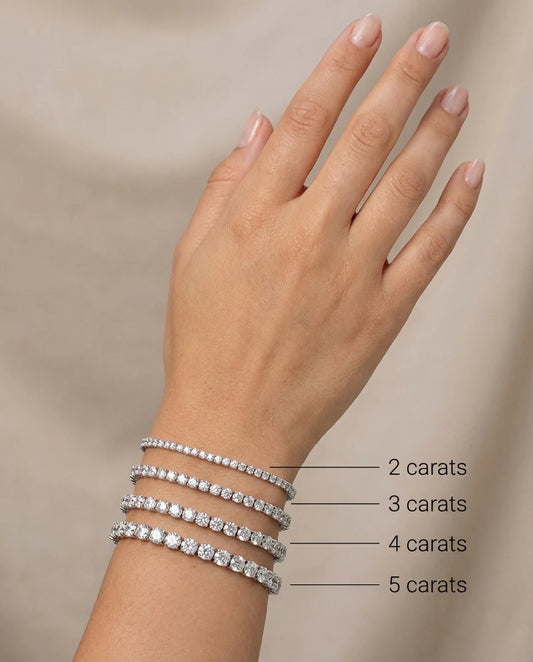 Hand wearing diamond bracelets with labeled carat weight on a neutral background
