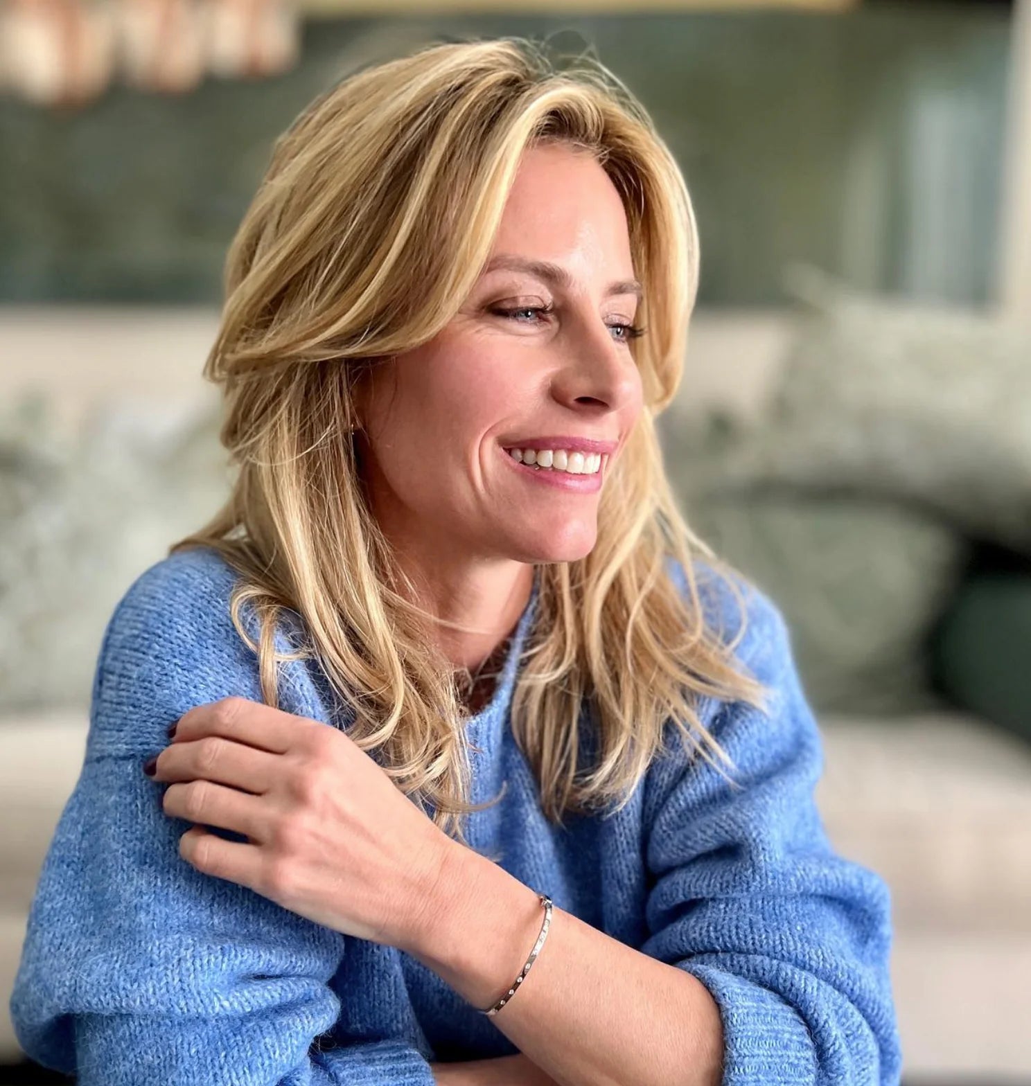 Woman in a blue sweater smiling in an indoor setting