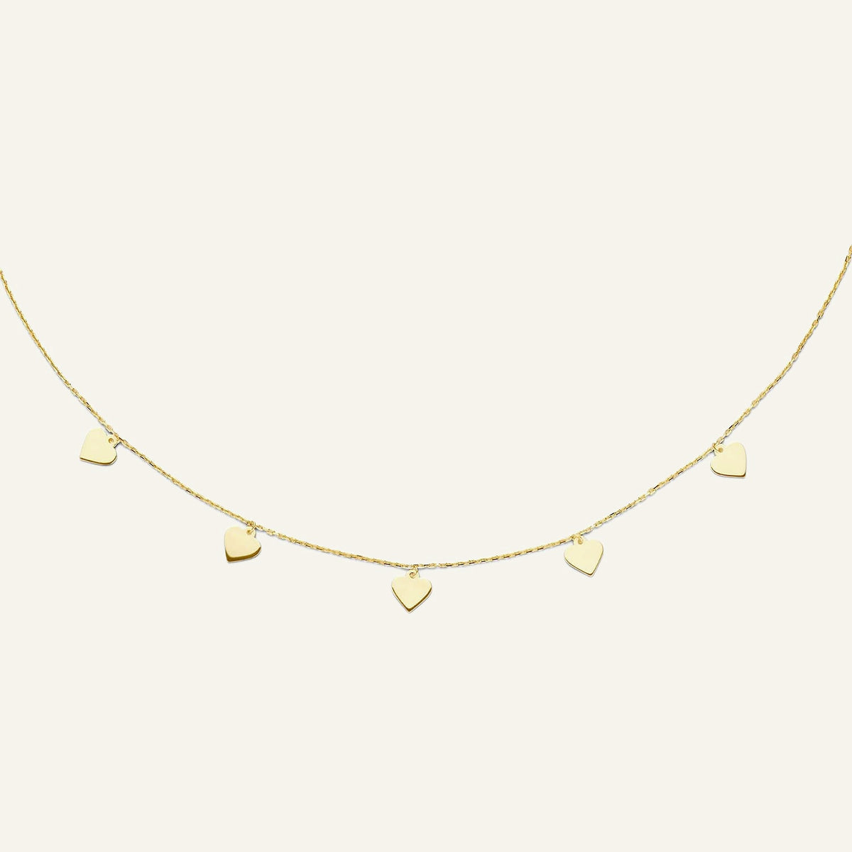 Jackie Amsterdam Hearts necklace in 14K yellow gold on pale beige background