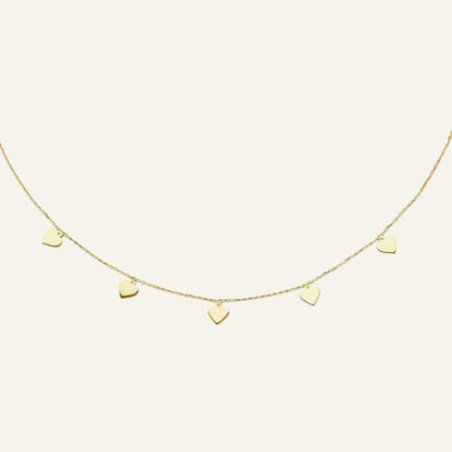 Jackie Amsterdam Hearts necklace in 14K yellow gold on pale beige background