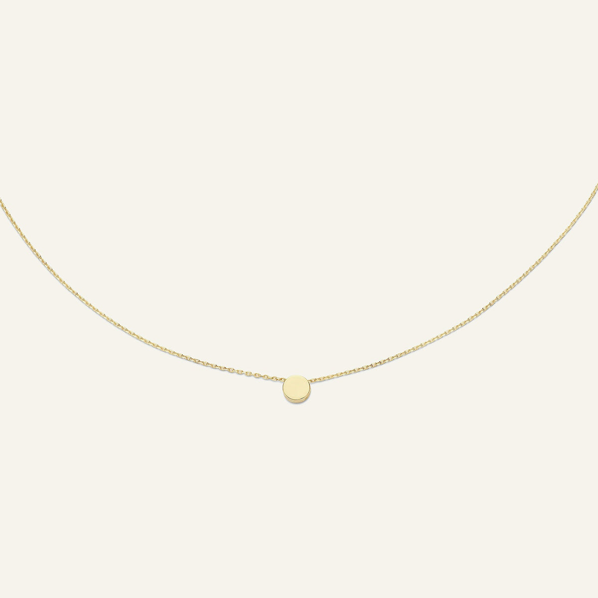 Jackie Amsterdam Plain Circle necklace in 14K yellow gold on pale beige background