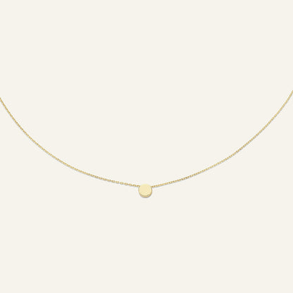 Jackie Amsterdam Plain Circle necklace in 14K yellow gold on pale beige background