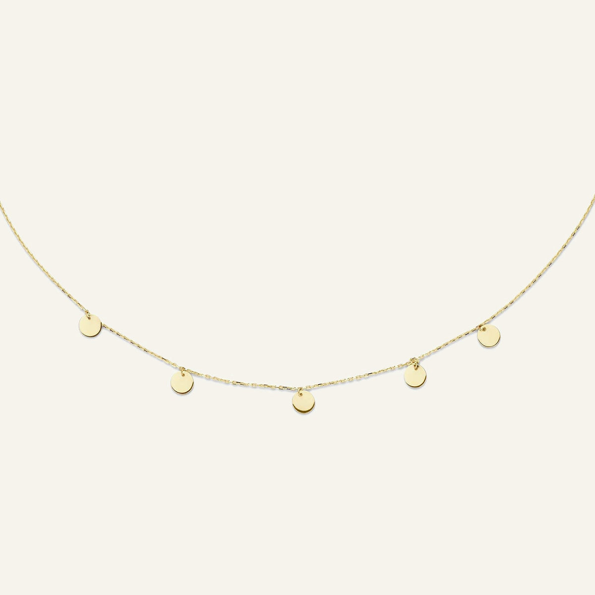 Jackie Amsterdam Disc necklace in 14K yellow gold on pale beige background