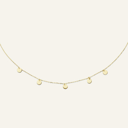 Jackie Amsterdam Disc necklace in 14K yellow gold on pale beige background