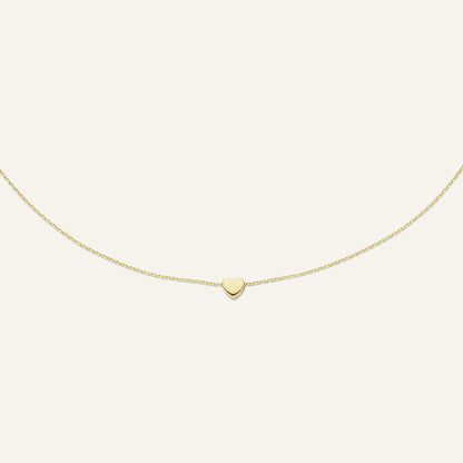 Jackie Amsterdam Plain Heart necklace in 14K yellow gold on pale beige background