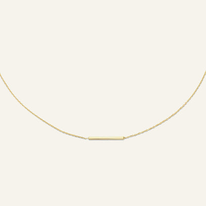 Jackie Amsterdam Bar necklace in 14K yellow gold on pale beige background