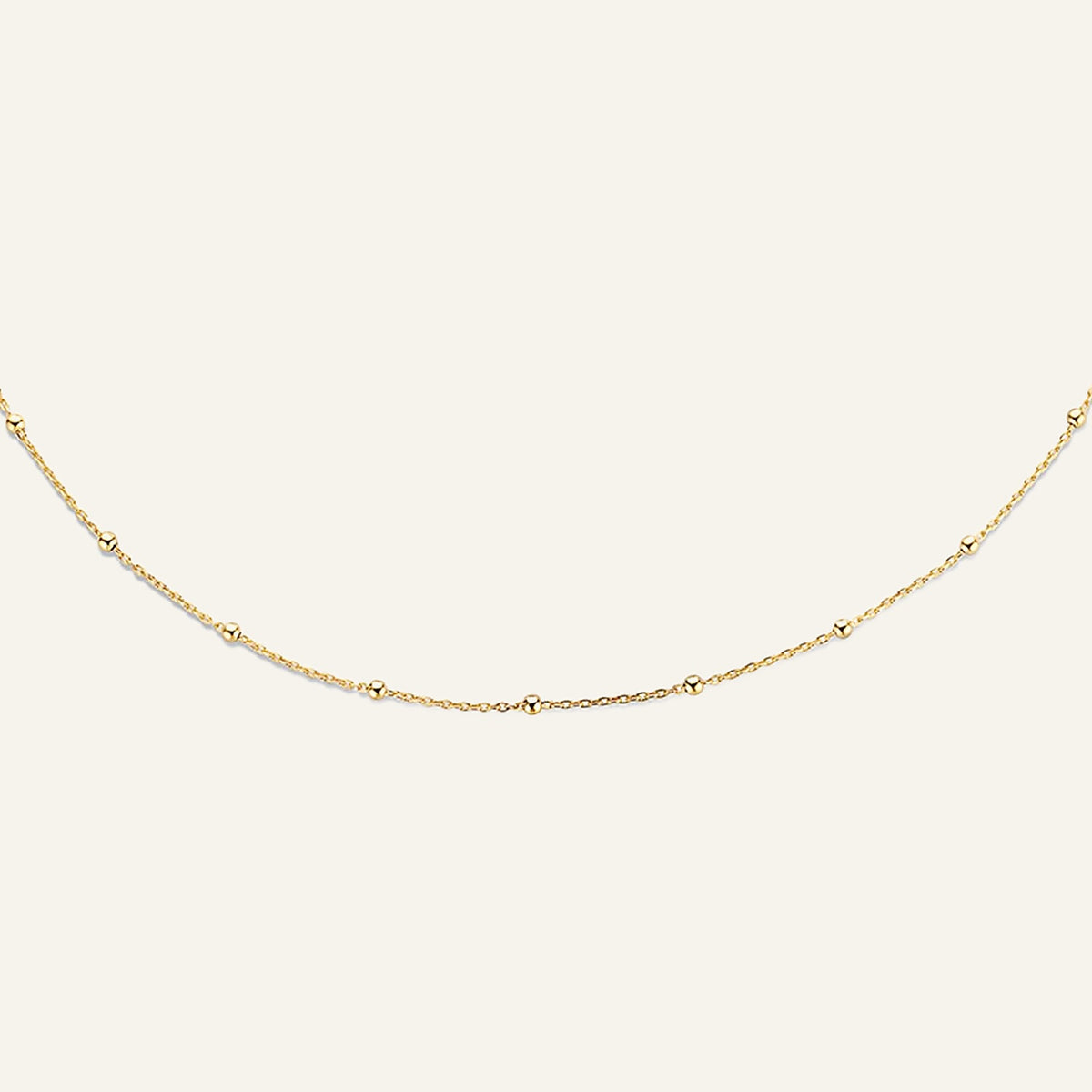 Jackie Amsterdam Dotted necklace in 14K yellow gold on pale beige background