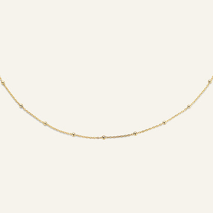 Jackie Amsterdam Dotted necklace in 14K yellow gold on pale beige background