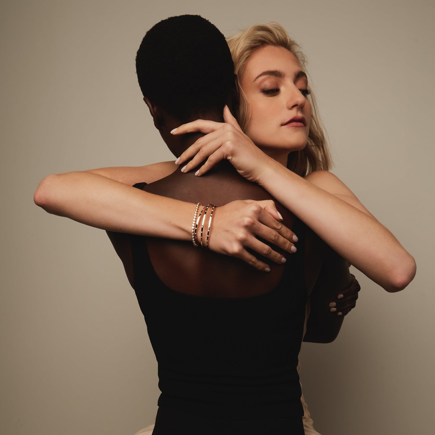 Woman in a black dress and beige pants against a plain background