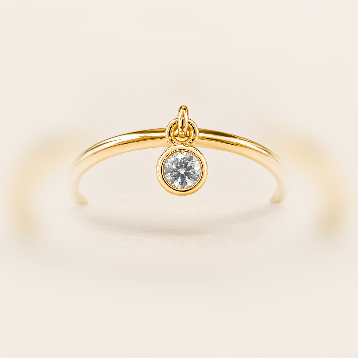 Round Bezel Diamond Charm Ring in Gold product photo on warm beige background