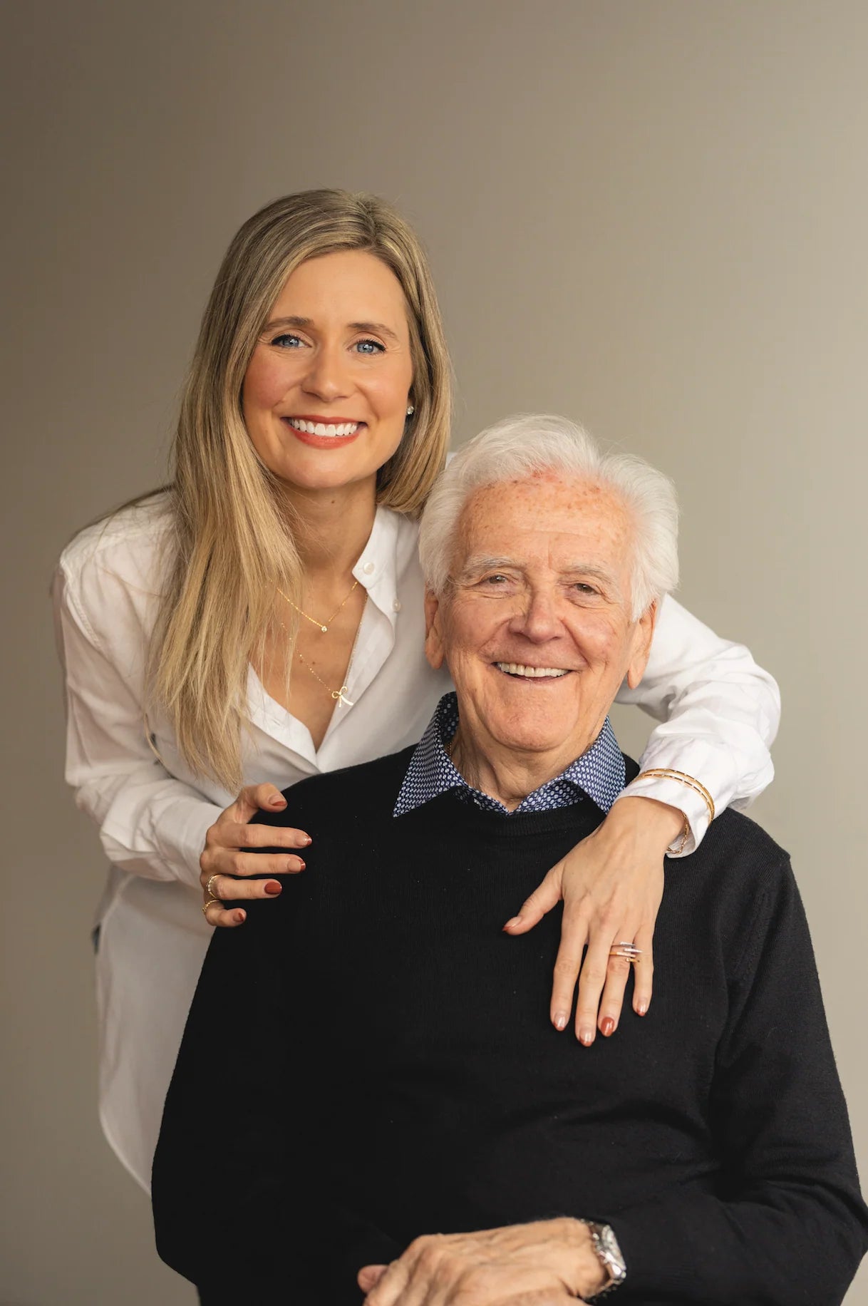 Woman embracing an older man against a plain background